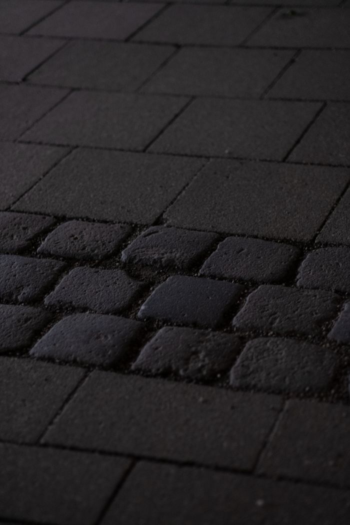 Close-up of a textured cobblestone pavement pattern at night, capturing the urban ambiance.