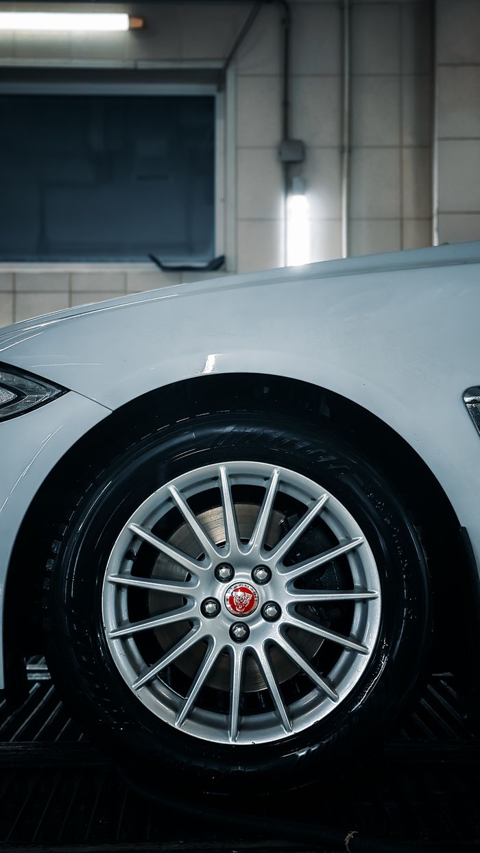 Close-up of a silver car wheel in a clean indoor garage setting, showcasing modern design.