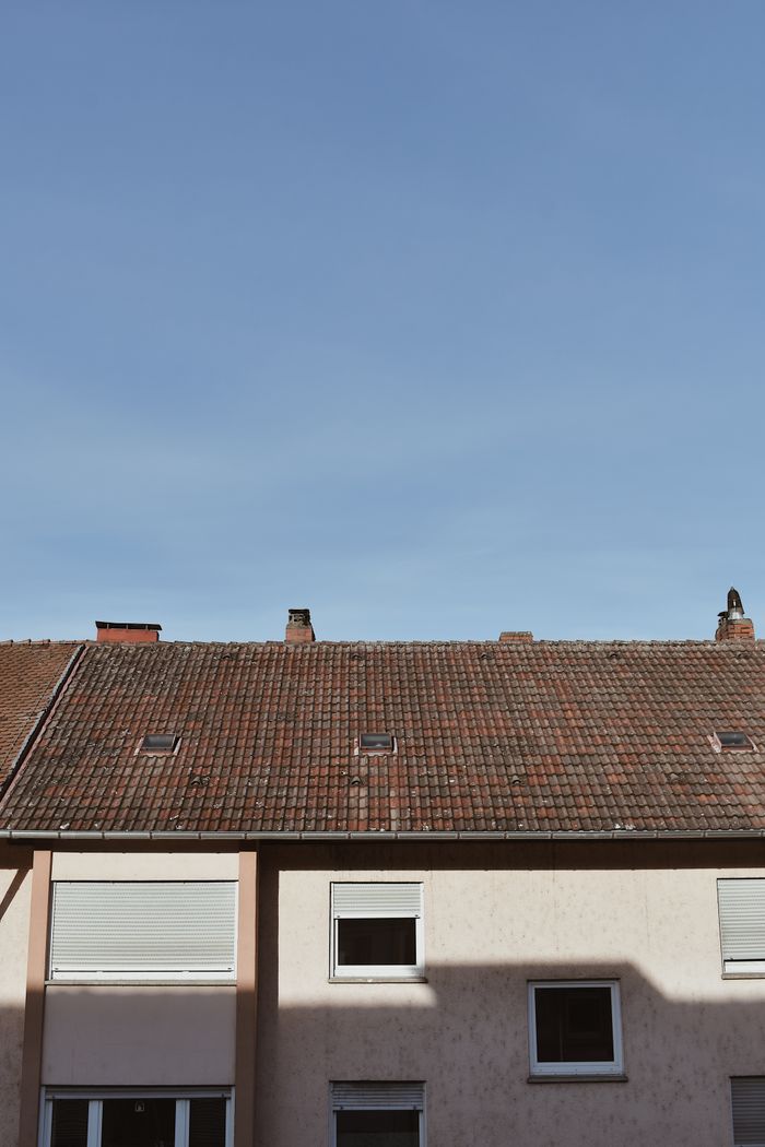 A minimalist view of a residential building roof against a clear blue sky, perfect for architectural themes.
