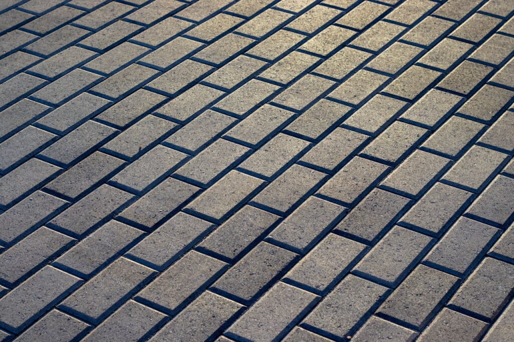 Sunlit outdoor stone pavement with a uniform brick pattern, ideal for backgrounds and architecture projects.