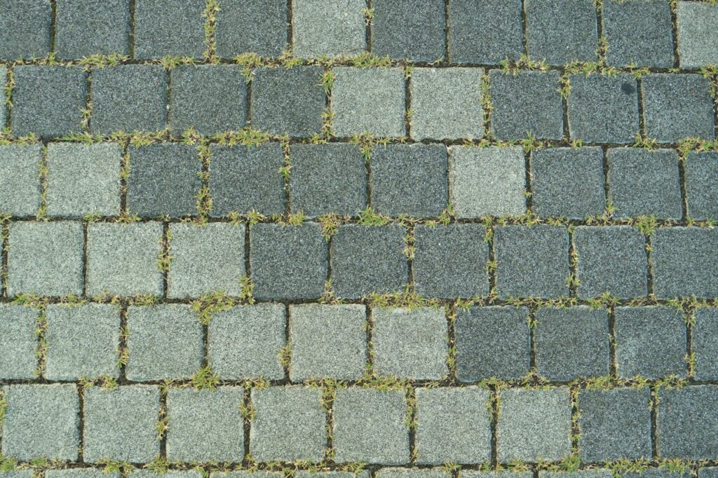 Close-up of a stone paved sidewalk with grass growing between the stones in Toyohashi, Japan.