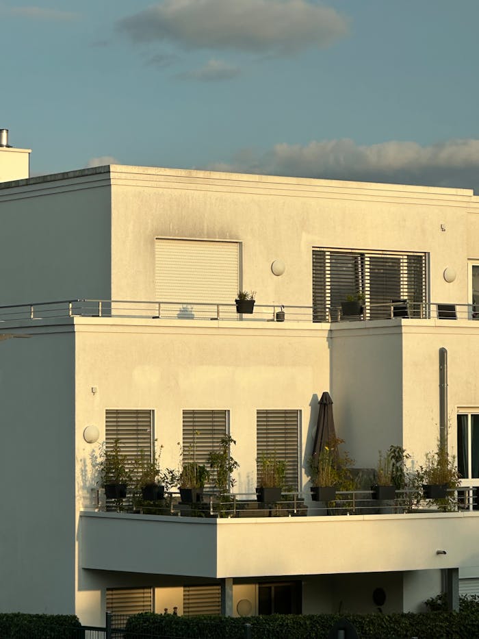 Contemporary white apartment building with balconies during golden hour lighting.